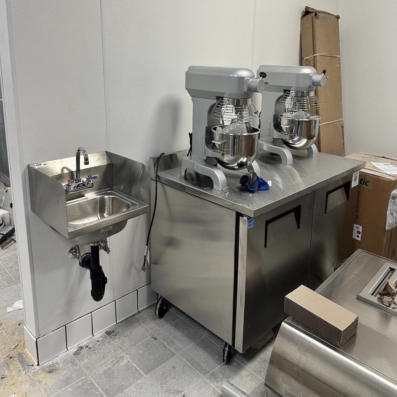 Commercial kitchen with stainless hand sink and equipment plumbed against a sanitary wall panel