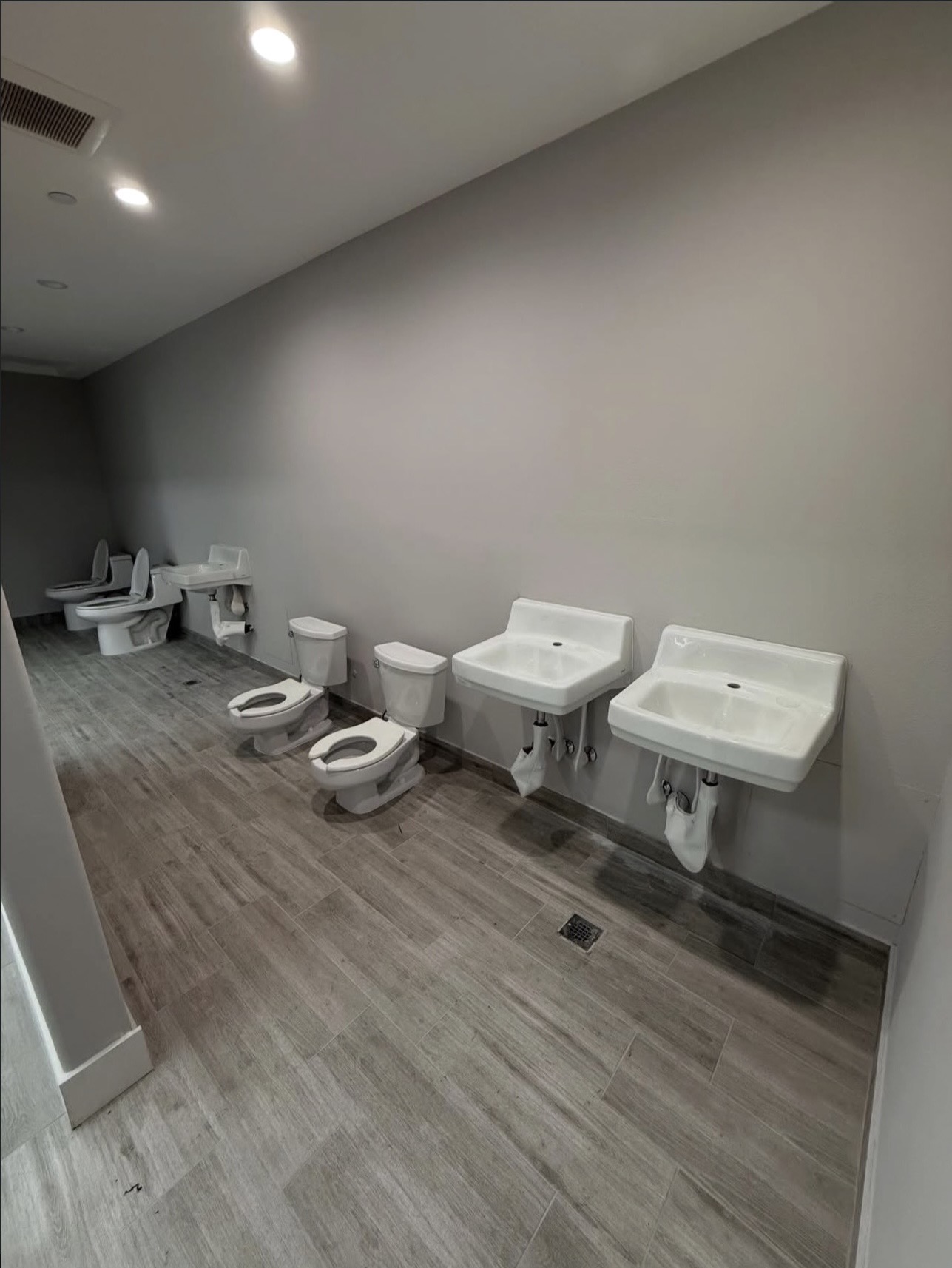 Commercial restroom fixtures staged for installation including toilets and wall-hung sinks