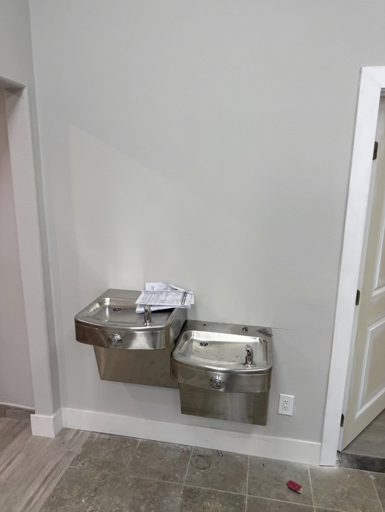Dual-height wall-mounted stainless drinking fountains installed in a corridor